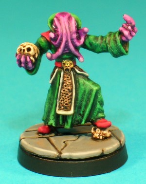 Pose 2, variant A. This Mind Flayer holds a skull in his right hand, and appears to be beckoning with his outreached left. He wears long robes with a high, stiff collar and plain cuffs, an ornate scalloped belt, and a backplate bearing a raised illithid skull design. This variant has 4 medium-length tentacles spread evenly around his face, with connecting webs visible between them.