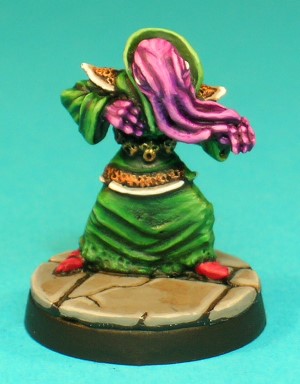 Pose 3, variant A. This Mind Flayer holds his right hand by his chest and his left partly extended forwards. He wears a decorated tunic with ornate epaulets and lower hem, over long robes with a high, stiff collar and plain cuffs, and a belt with a repeated 'screaming head' design. This variant has 4 long tentacles running along the left arm, with connecting webs just visible between them.