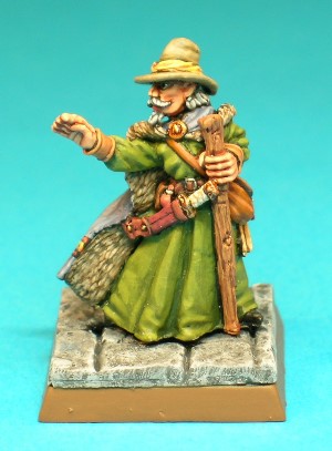 Figure 3, Magic User.<br>This is an archetypal Wizard character, wearing long robes, a fur-lined cloak and a broad-brimmed hat. He holds a simple wooden staff in his left hand and carries a long dagger sheathed at his belt.
